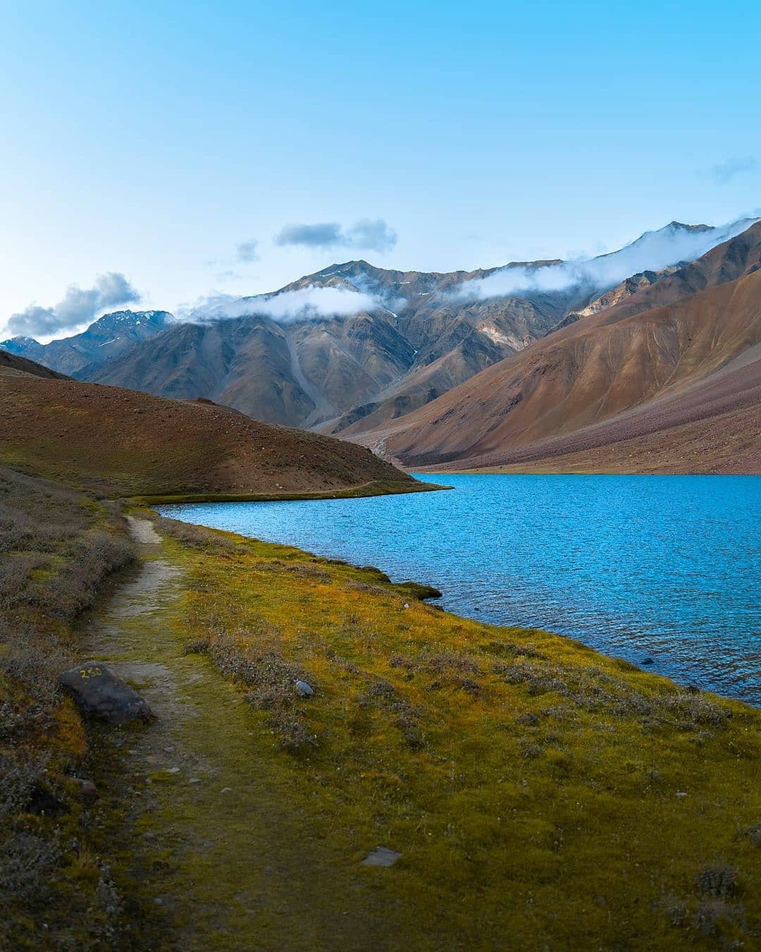 Breathtaking view of the turquoise Chandartal Lake surrounded by the brown, rugged mountains of Spiti Valley.