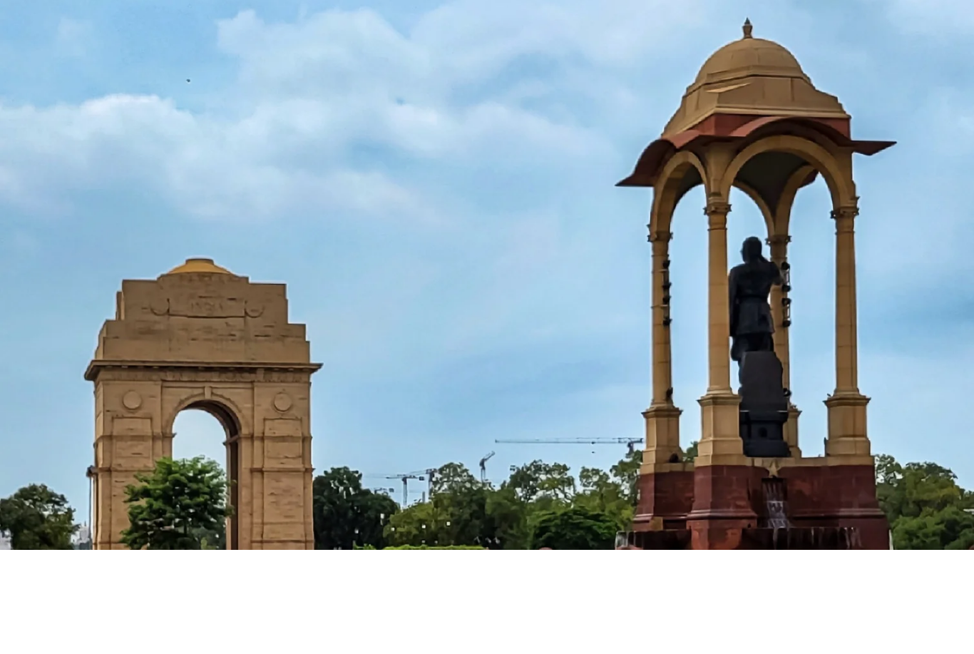 The India Gate war memorial arch and the National War Memorial canopy in New Delhi, surrounded by lush green lawns.