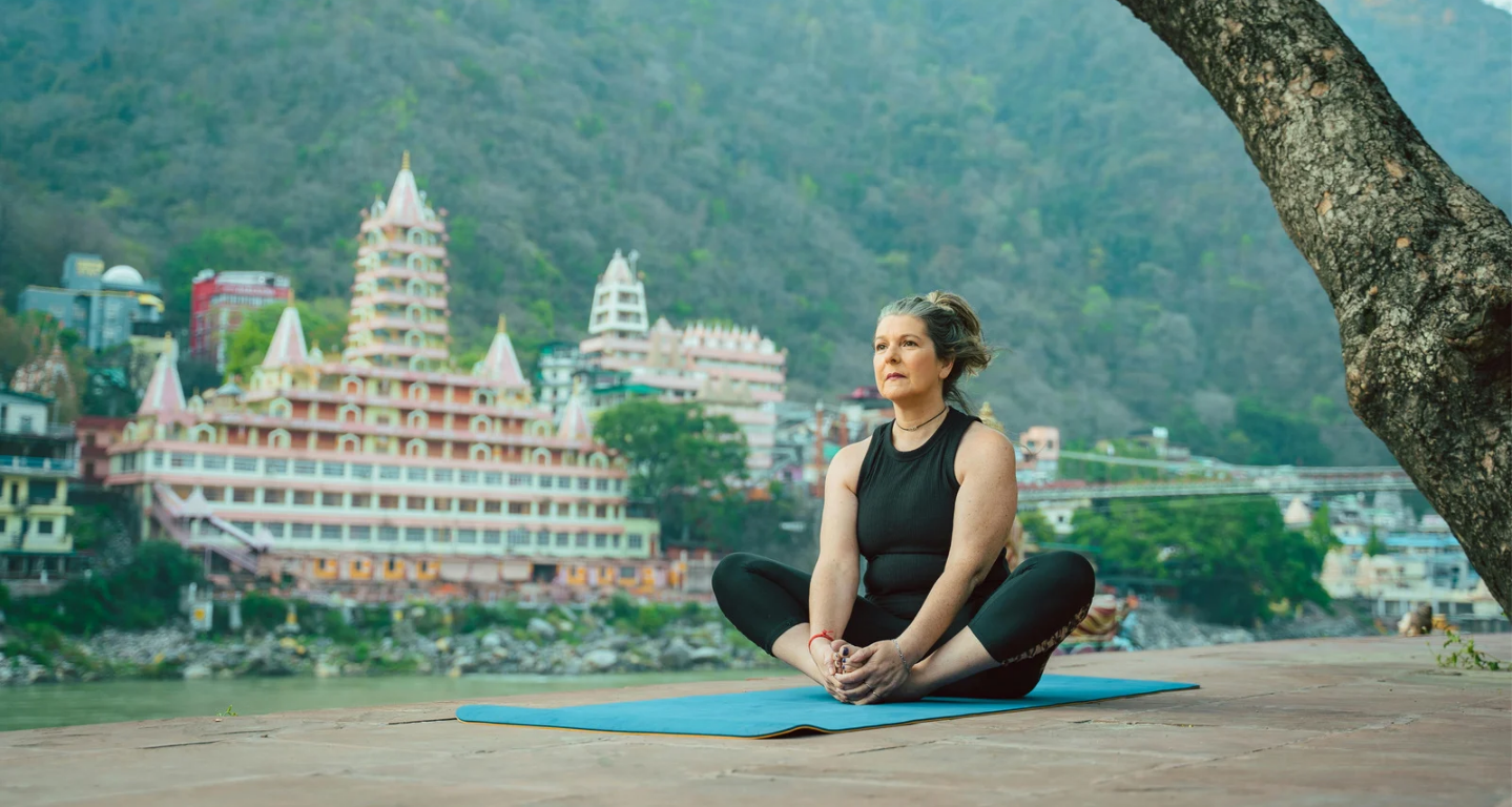 The Lakshman Jhula suspension bridge over the blue Ganges River surrounded by temples in Rishikesh, Uttarakhand.